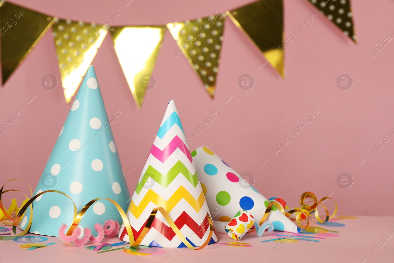 Photo of Colorful party hats and festive items on pink background. Space for text