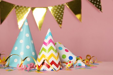 Colorful party hats and festive items on pink background. Space for text