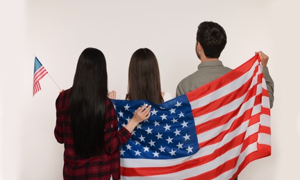 Photo of 4th of July - Independence Day of USA. Family with American flags on white background, back view