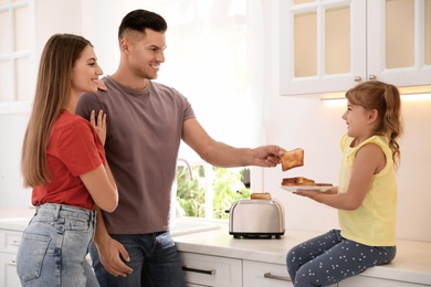 Photo of Happy family using modern toaster in kitchen