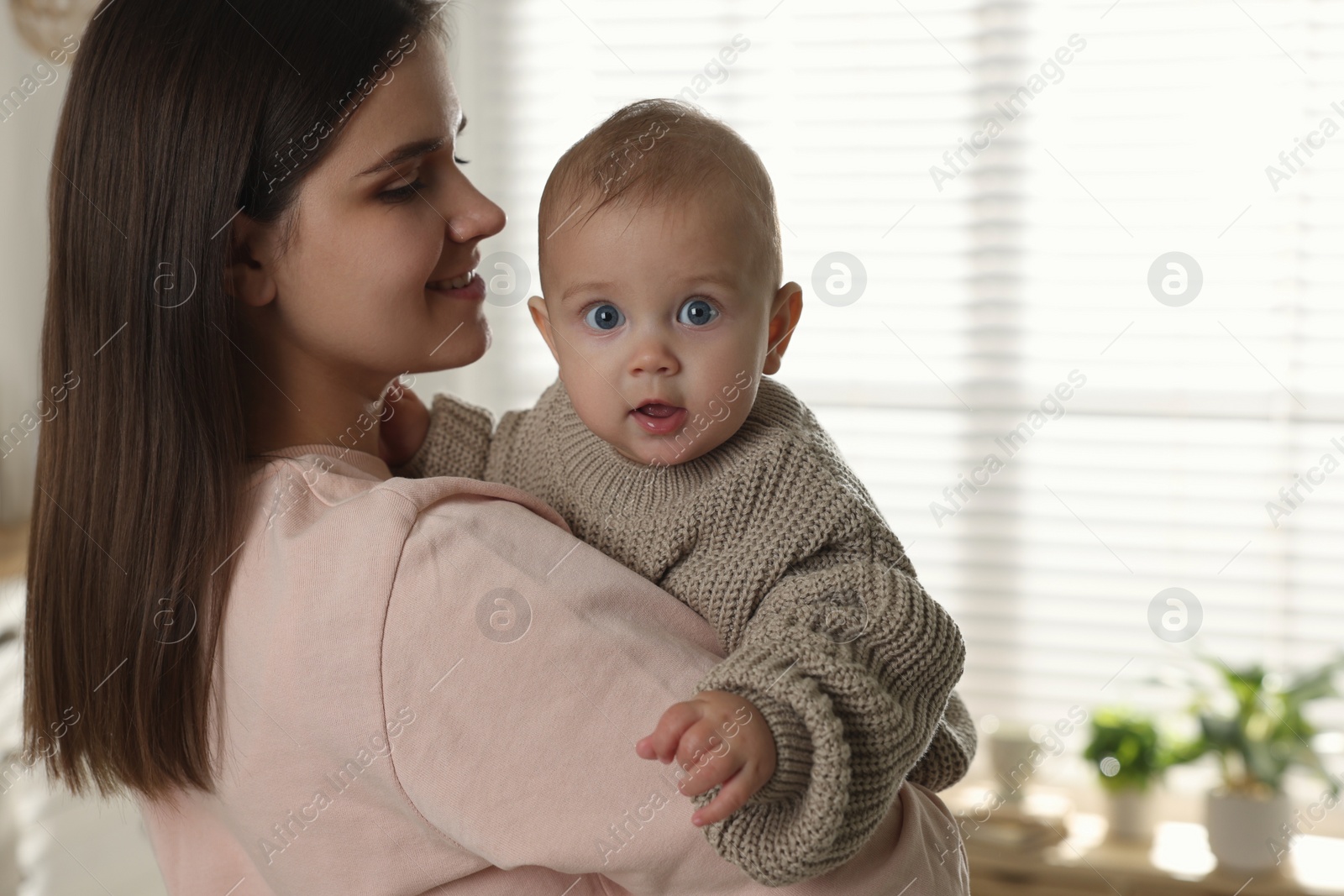 Photo of Happy young mother with her baby at home. Space for text