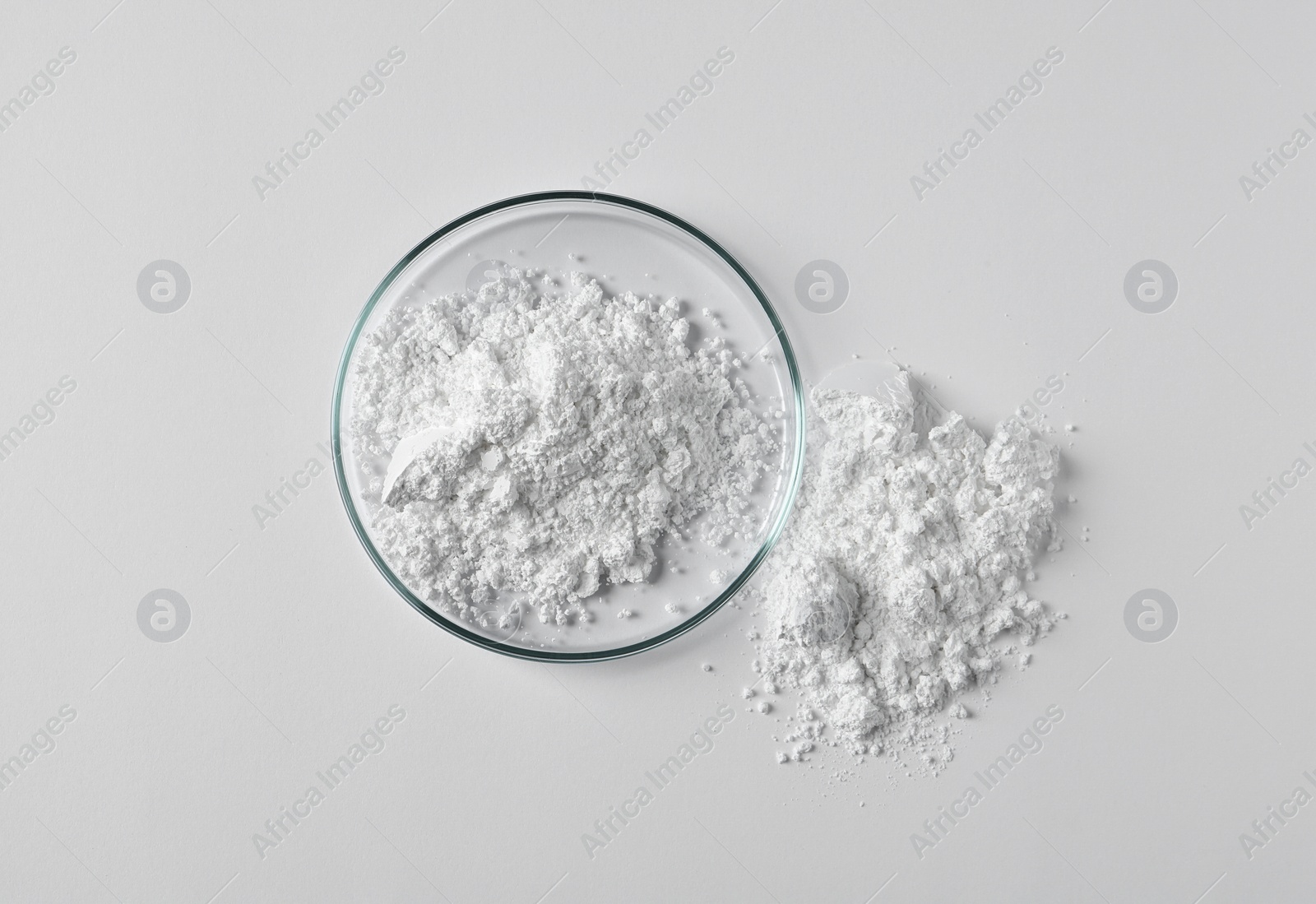 Photo of Petri dish and calcium carbonate powder on white background, top view