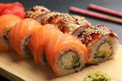 Photo of Delicious sushi rolls on wooden tray, closeup