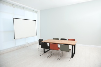 Conference room interior with wooden table and video projection screen