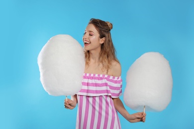 Portrait of pretty young woman with cotton candy on blue background