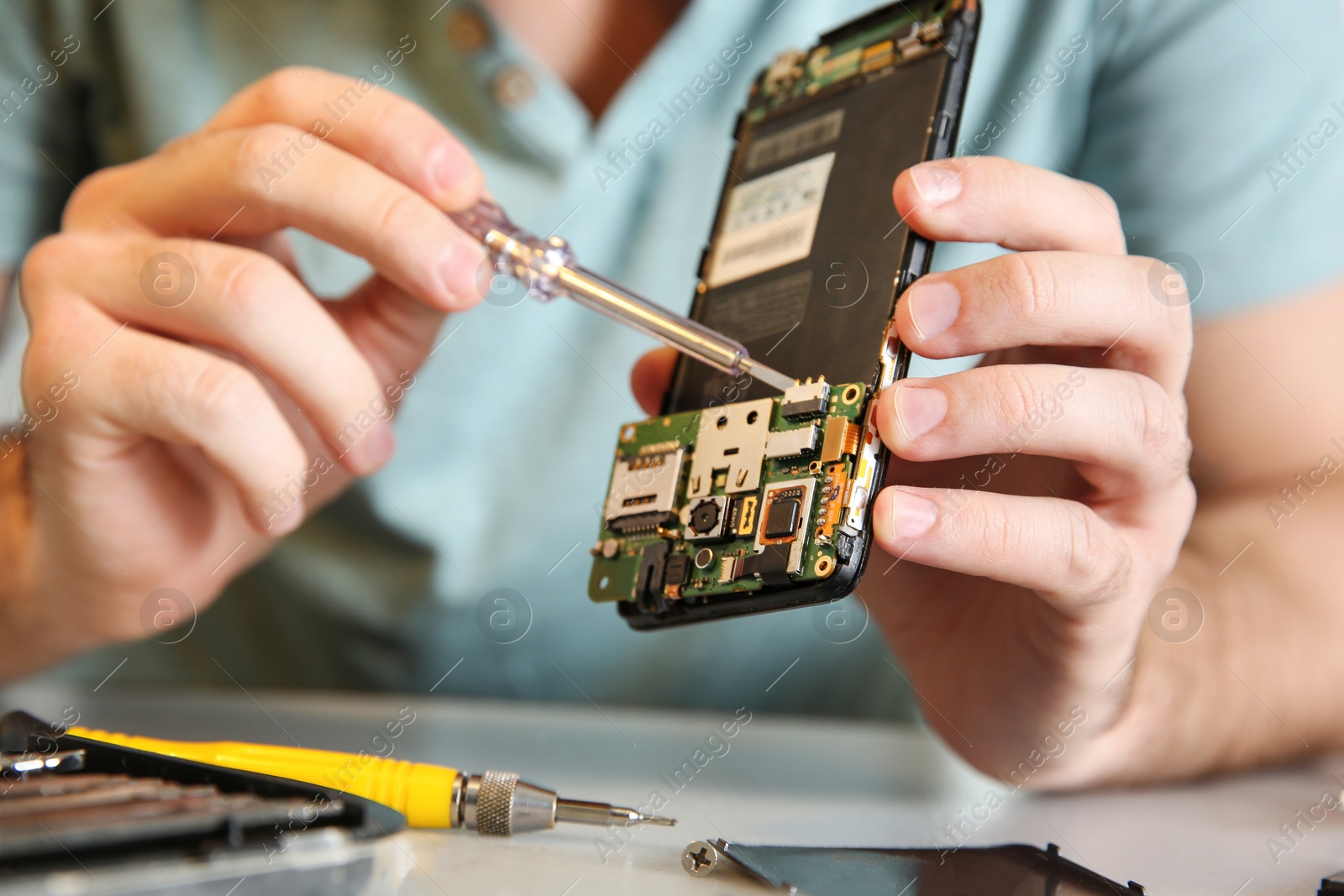 Photo of Technician repairing mobile phone at table, closeup