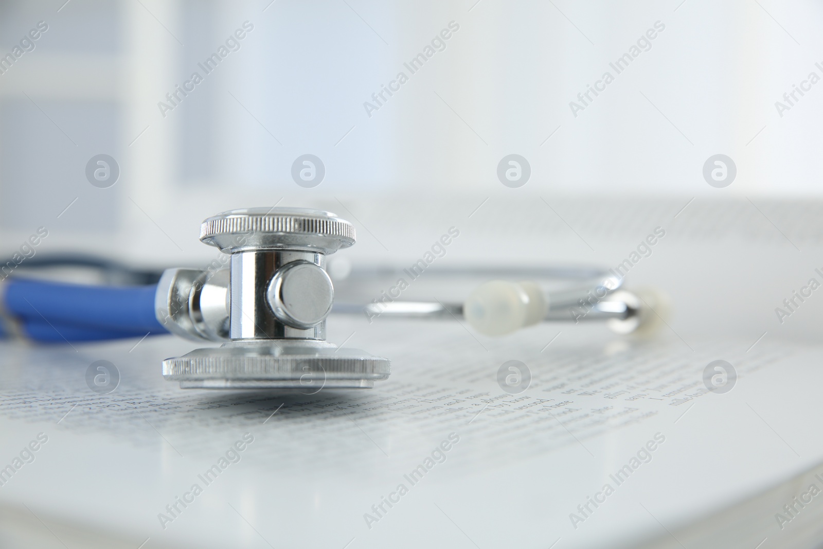 Photo of One medical stethoscope and book on table, closeup