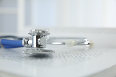 One medical stethoscope and book on table, closeup