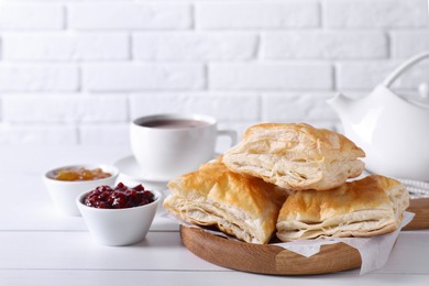 Photo of Delicious puff pastry served on white wooden table against brick wall