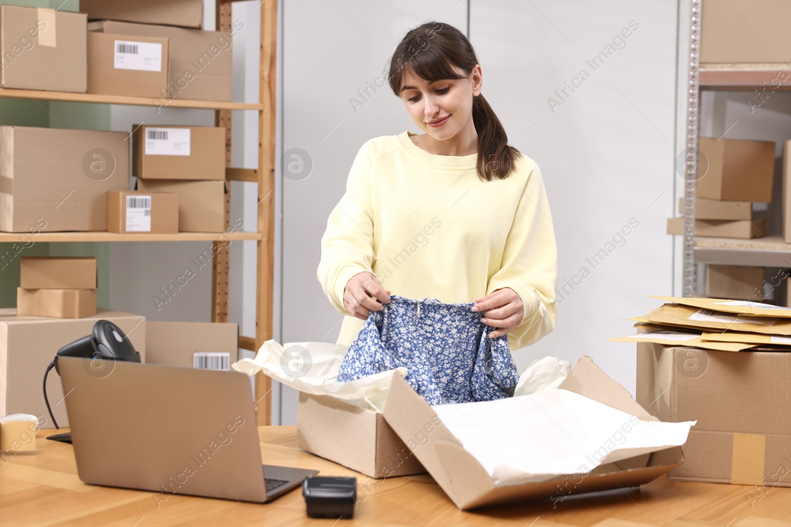 Photo of Post office worker packing parcel at wooden table indoors