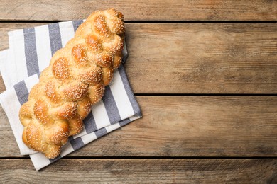 Photo of Homemade braided bread with sesame seeds on wooden table, top view and space for text. Traditional Shabbat challah