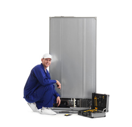 Male technician repairing refrigerator on white background