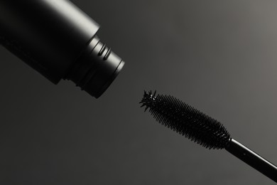 Black mascara with wand on grey background, closeup