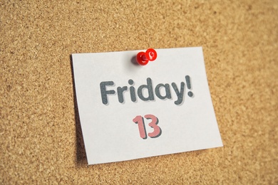 Photo of Paper note with phrase Friday! 13 pinned to cork background. Bad luck superstition