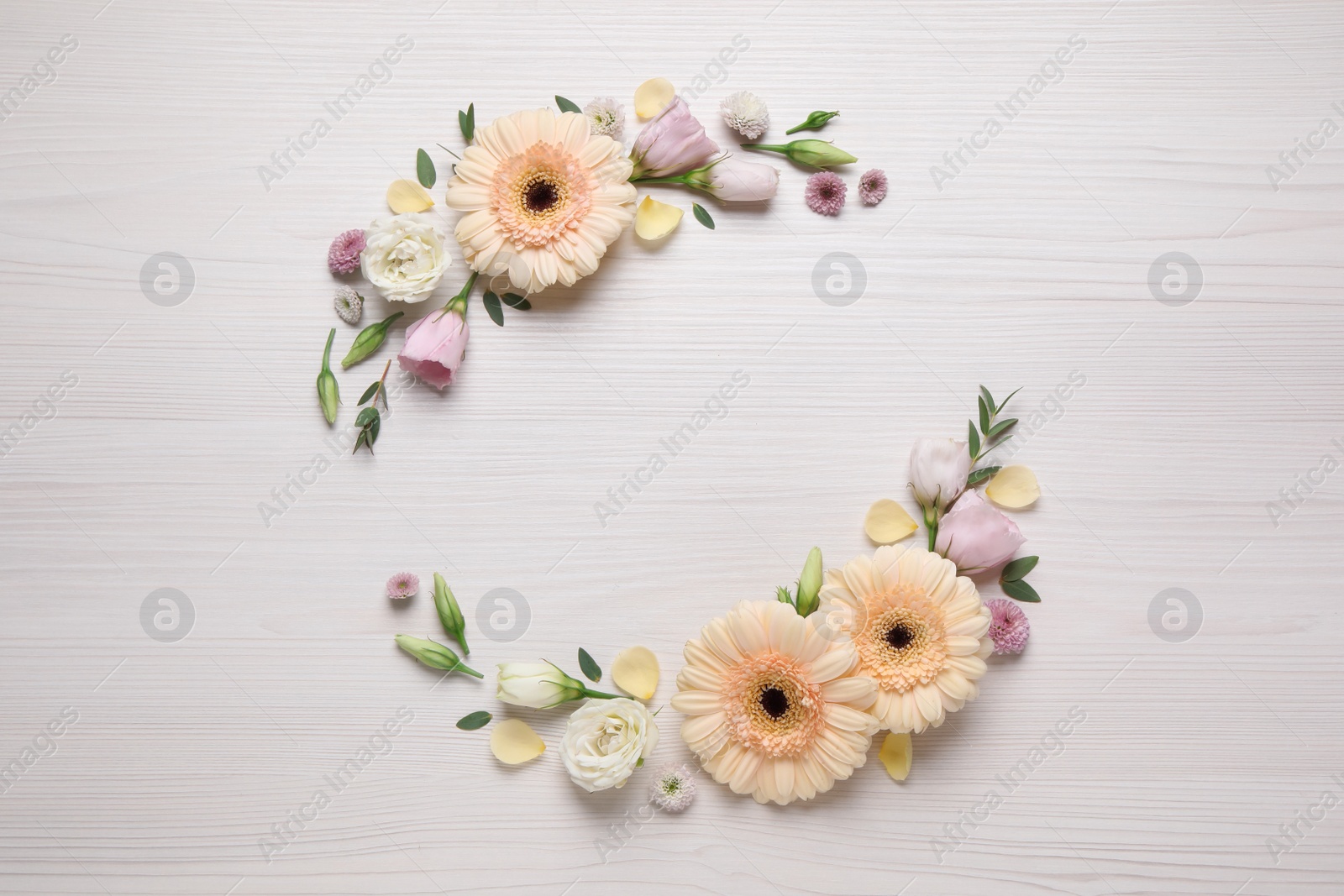 Photo of Wreath made of beautiful flowers and green leaves on white wooden background, flat lay. Space for text