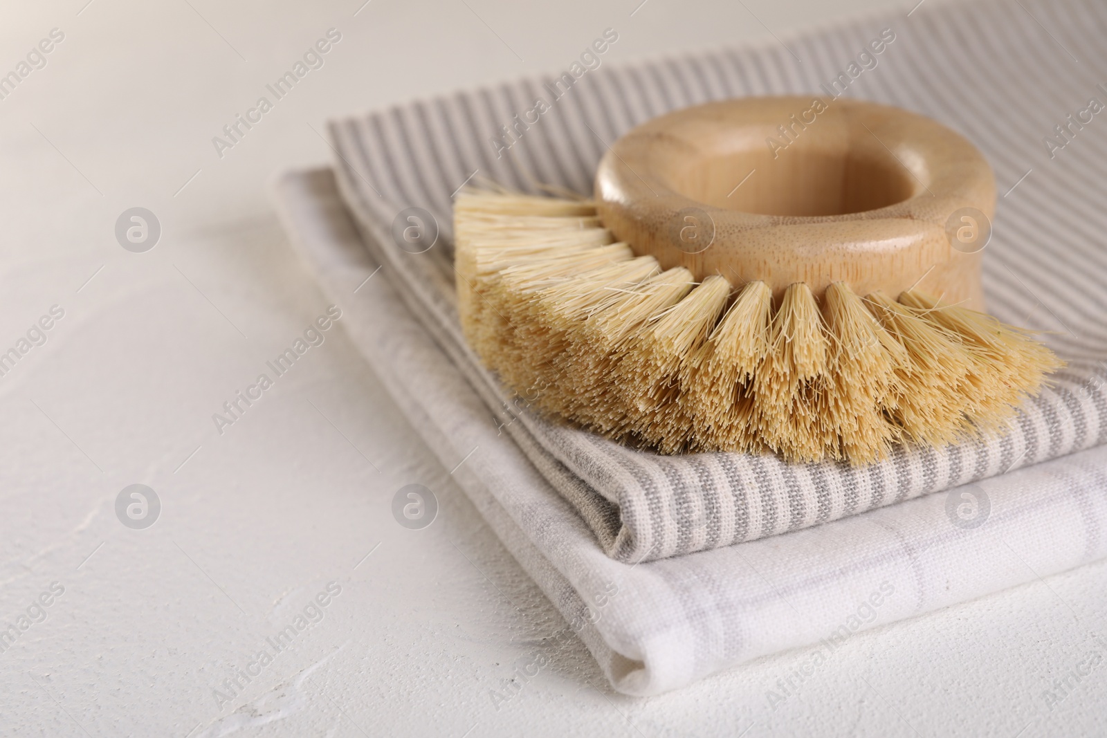 Photo of One cleaning brush and rag on white textured table, closeup. Space for text