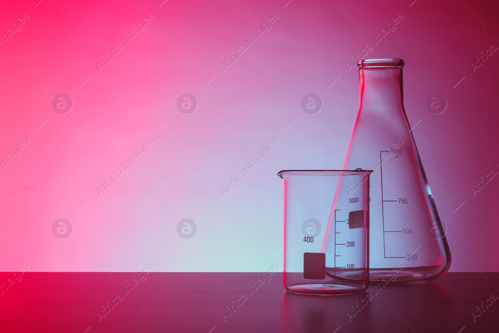 Photo of Empty chemistry laboratory glassware on table against color background