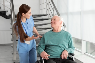 Photo of Nurse assisting senior man in wheelchair at hospital