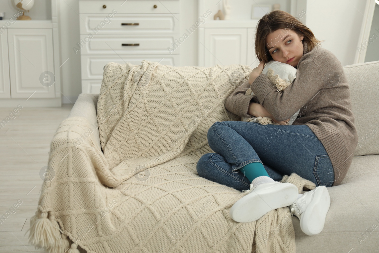 Photo of Sad young woman sitting on sofa at home, space for text