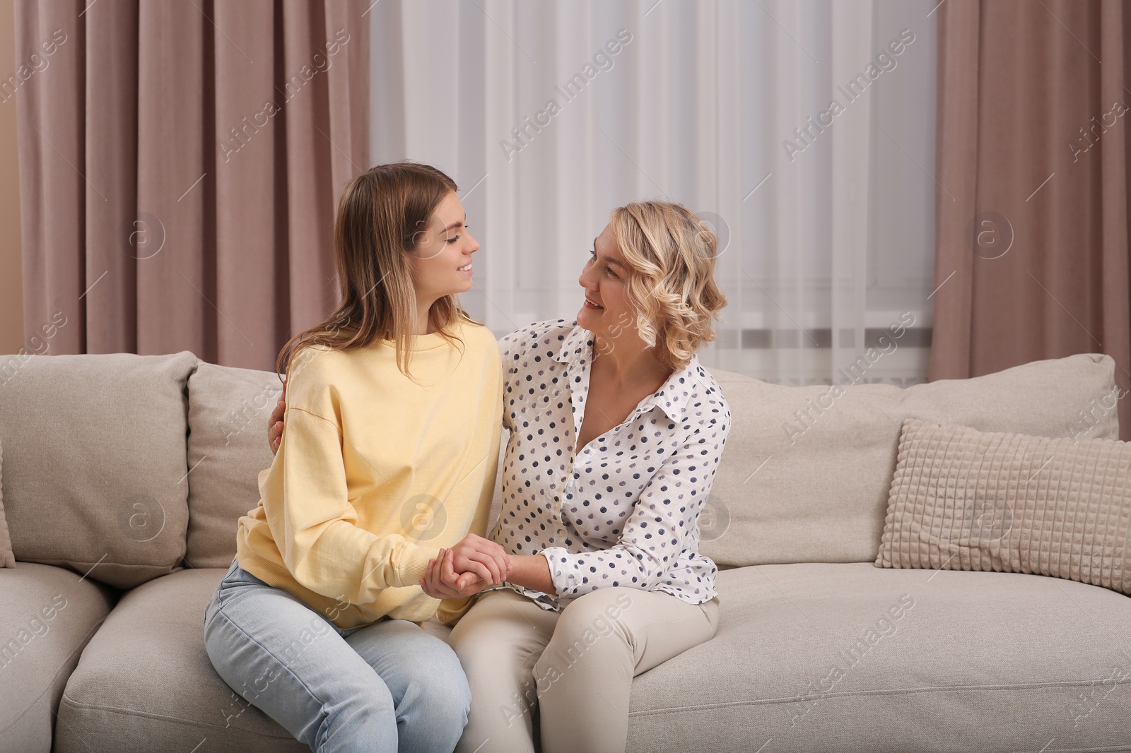 Photo of Young woman with her mom on sofa at home. Happy Mother's Day