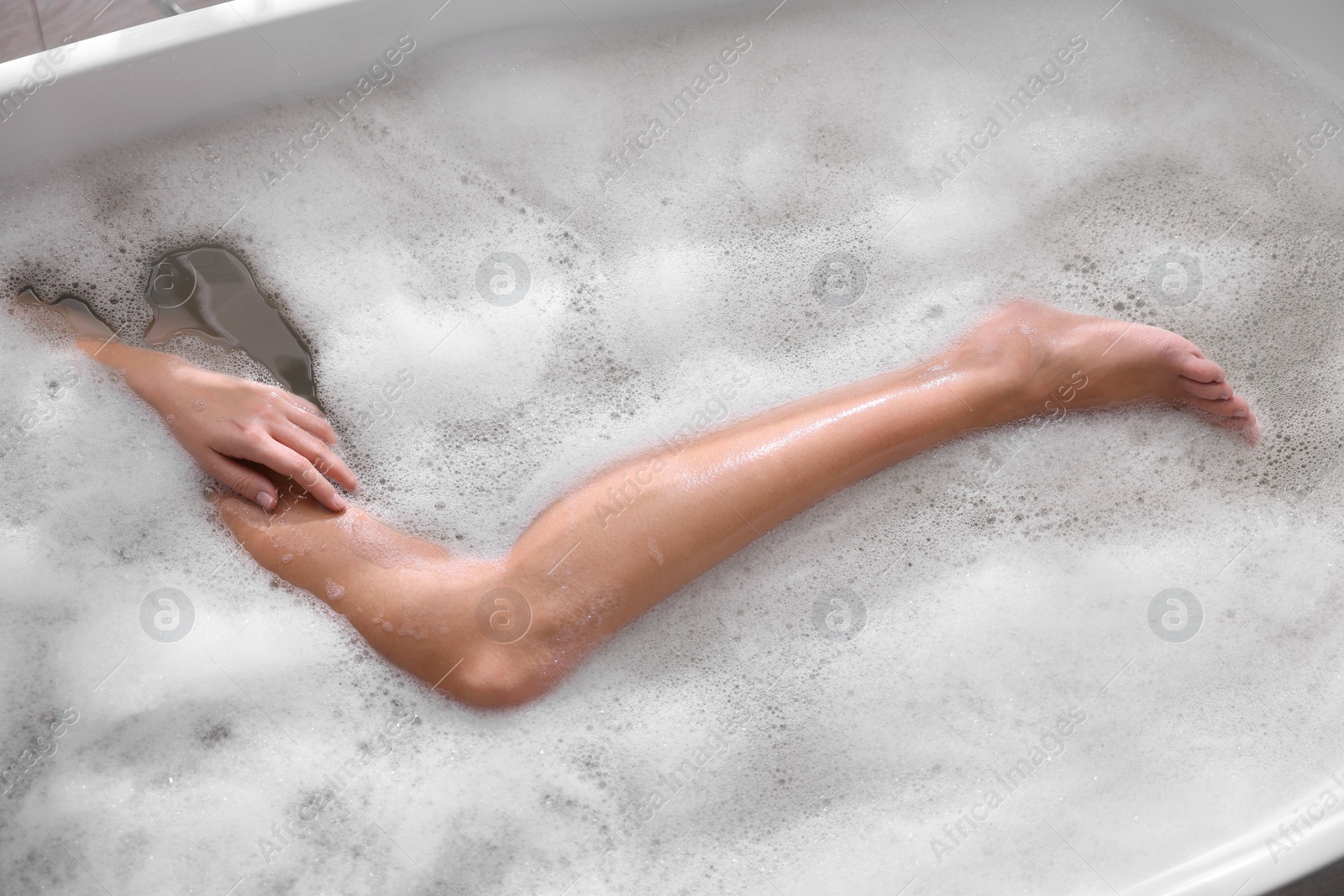 Photo of Woman taking bath in tub with foam, top view