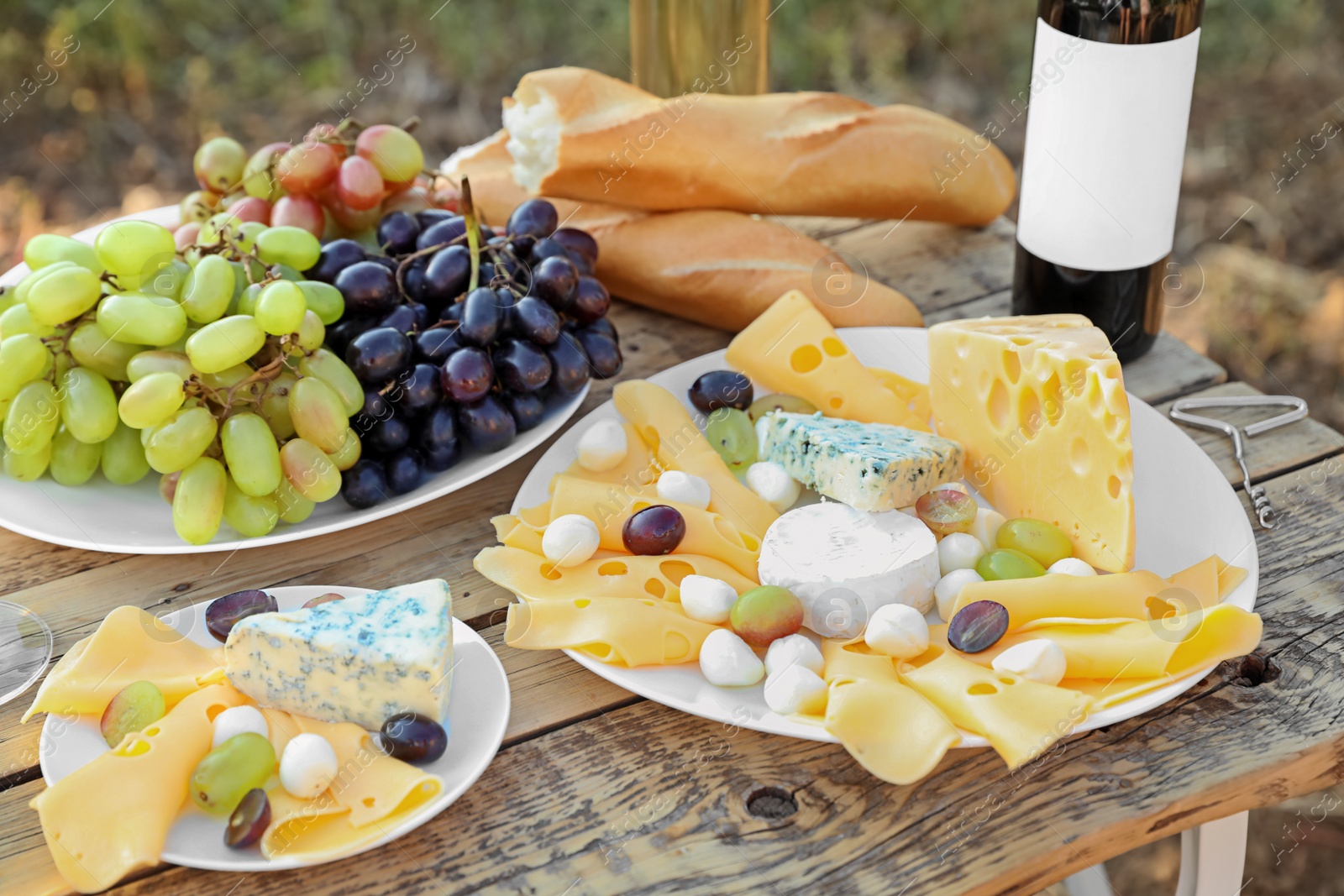 Photo of Wine, cheese and grapes on wooden table. Vineyard picnic