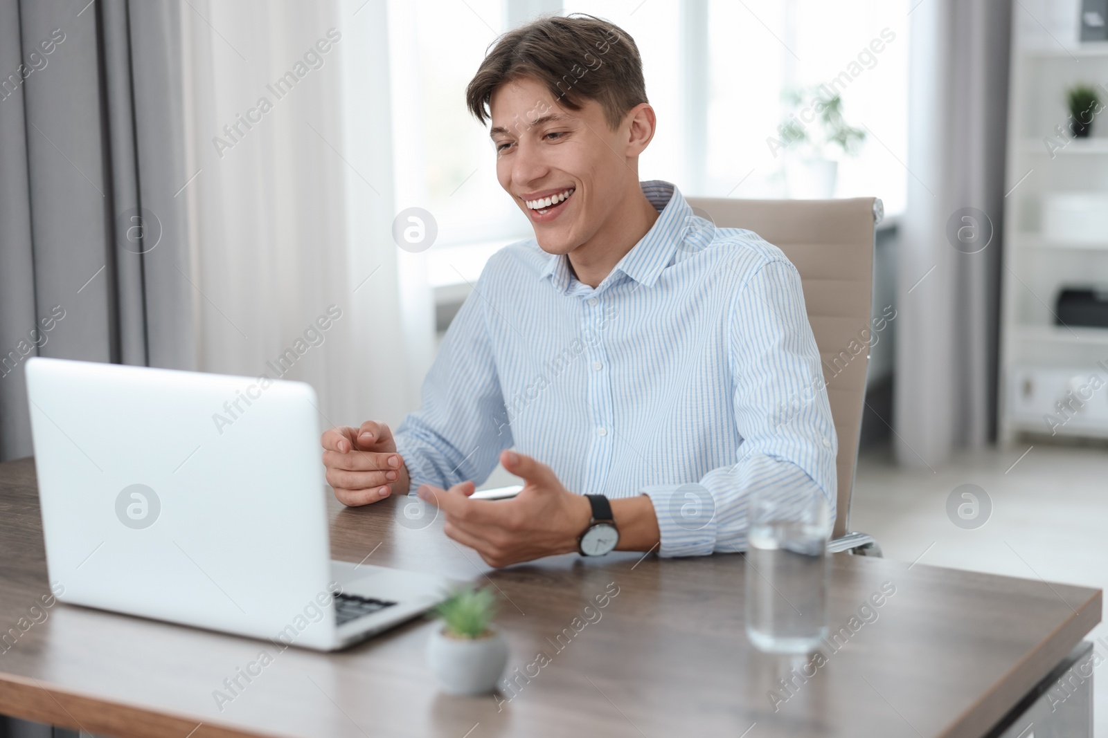 Photo of Man using video chat during webinar at wooden table in office