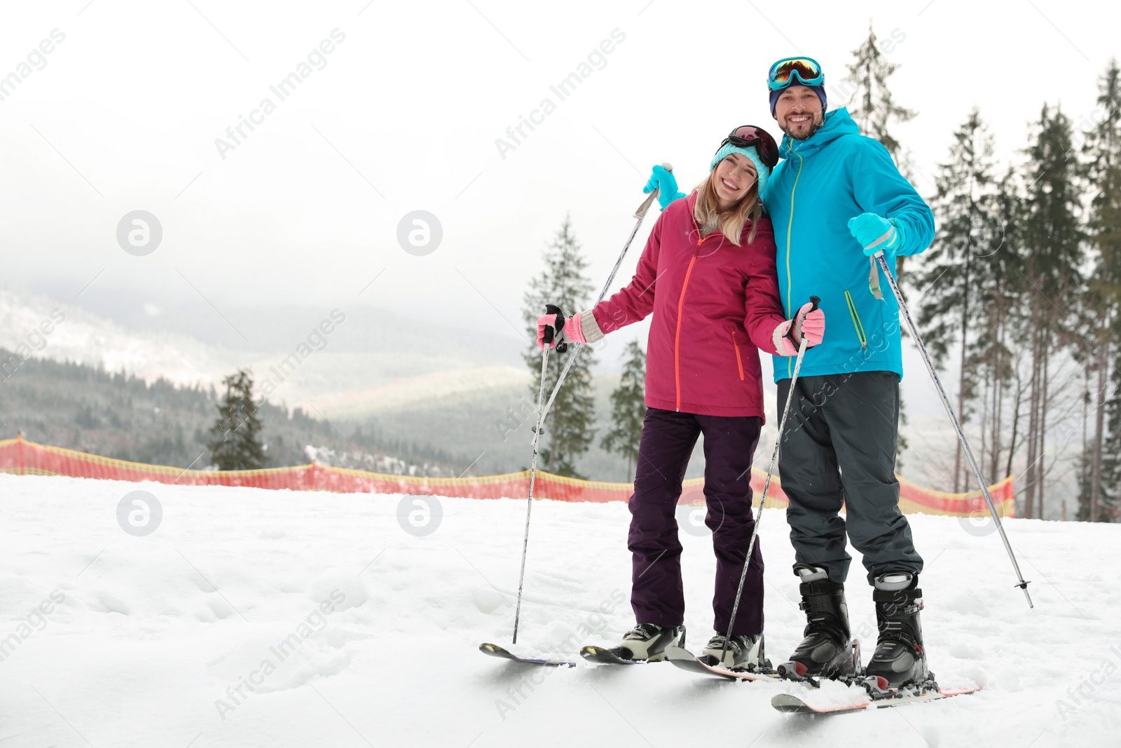 Photo of Couple of skiers on slope at resort, space for text. Winter vacation