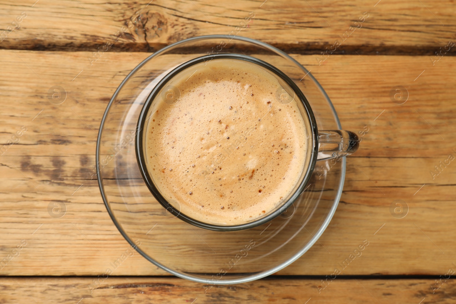 Photo of Cup of aromatic coffee on wooden table, top view