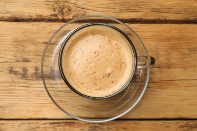 Photo of Cup of aromatic coffee on wooden table, top view