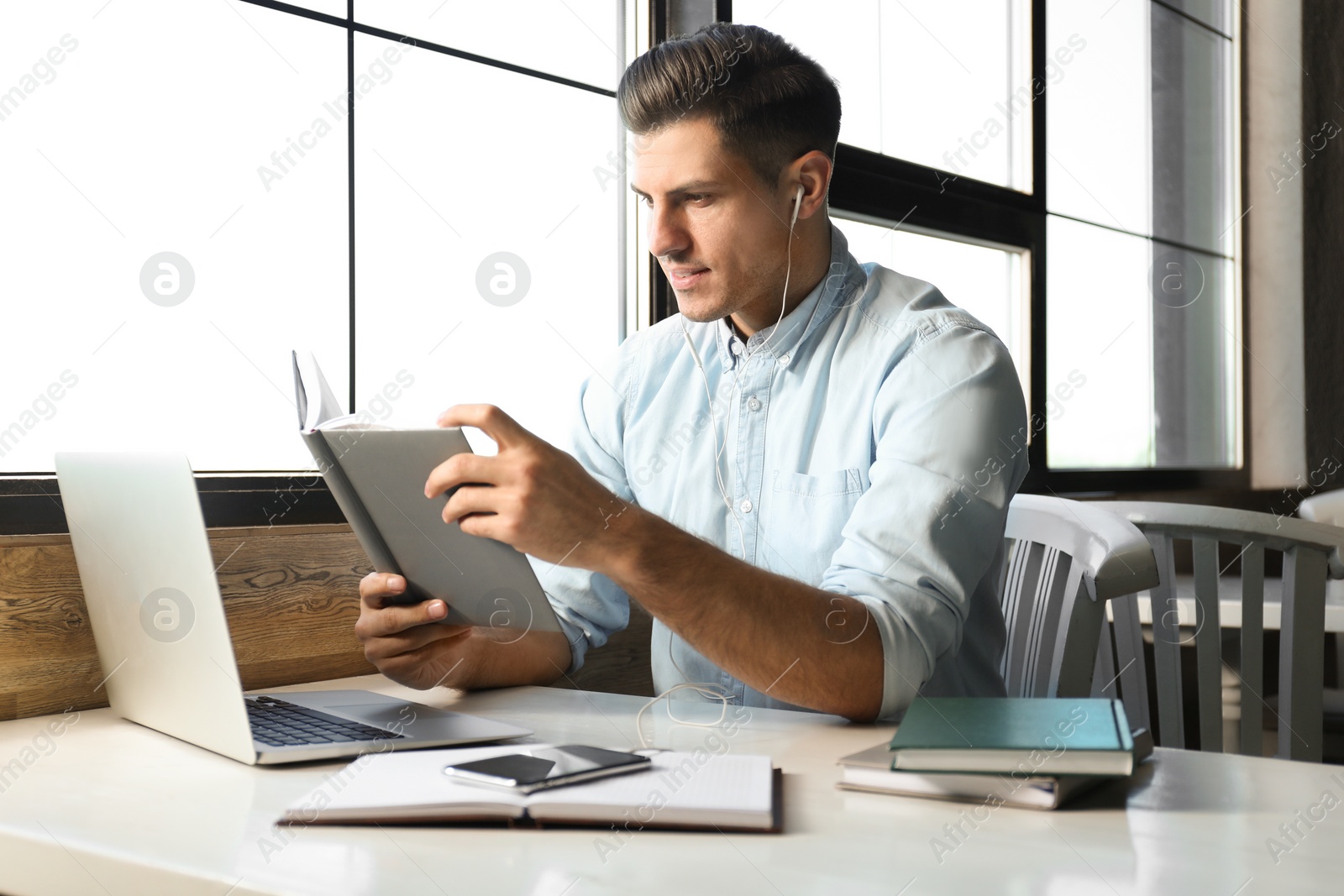 Photo of Man listening to audiobook at table in cafe