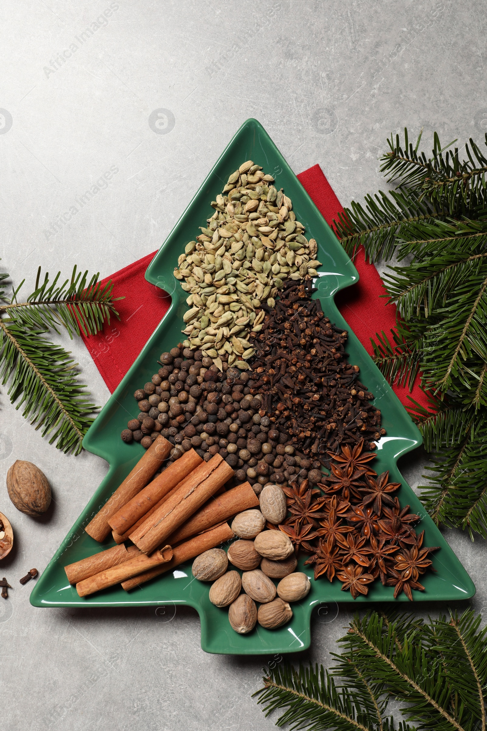 Photo of Different spices, nuts and fir branches on light gray textured table, flat lay