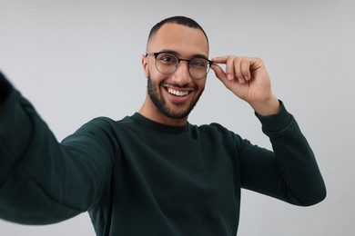 Photo of Smiling young man taking selfie on grey background