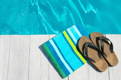 Beach accessories on wooden deck near swimming pool, top view. Space for text