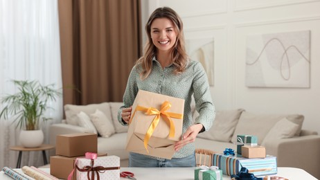 Photo of Young woman with beautifully wrapped gifts in living room