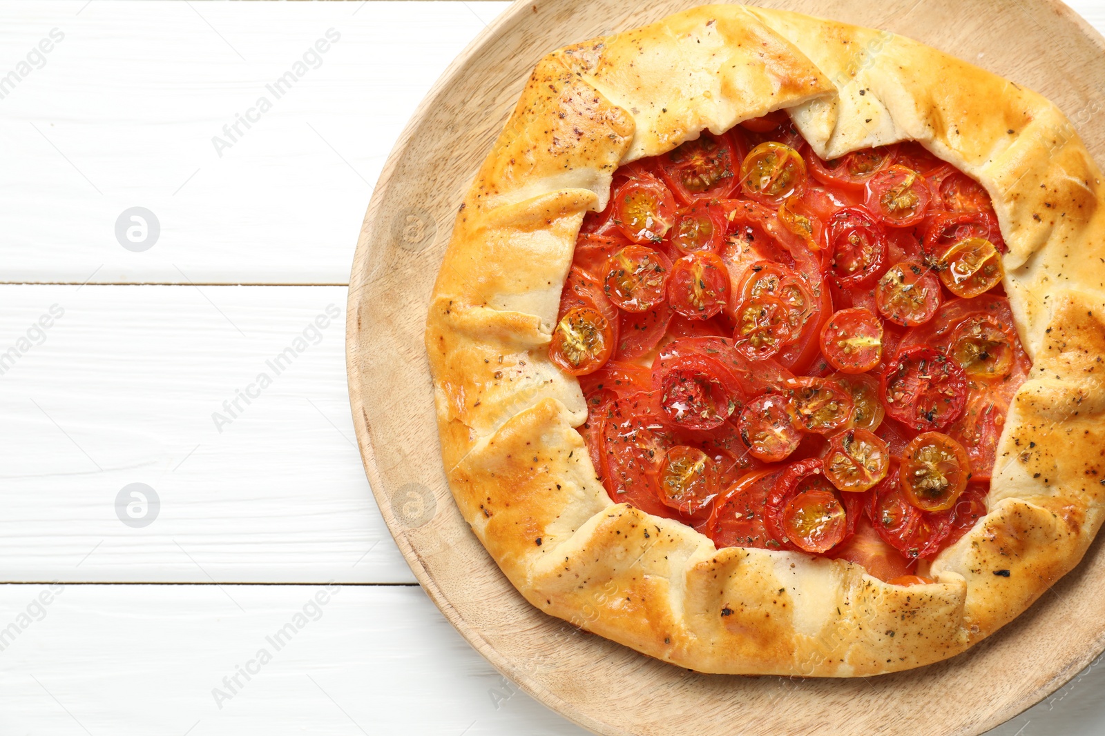 Photo of Tasty tomato galette (Caprese galette) on white wooden table, top view. Space for text