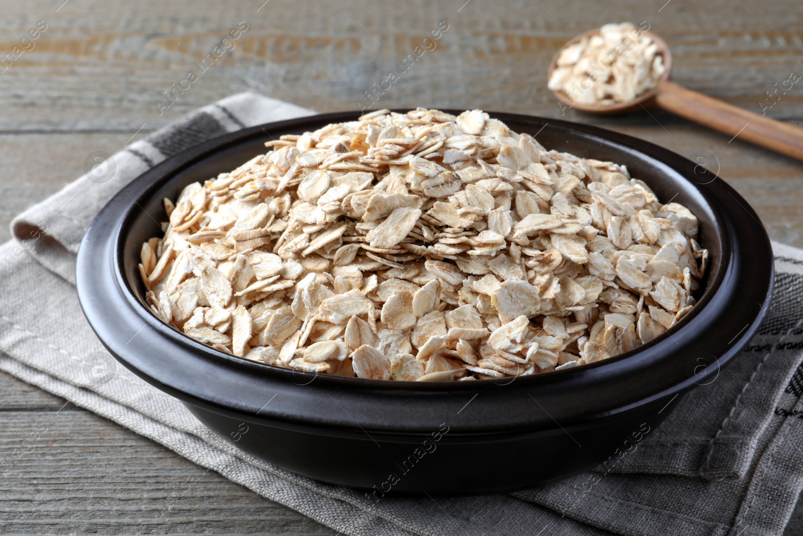 Photo of Bowl of oatmeal and spoon on wooden table, closeup