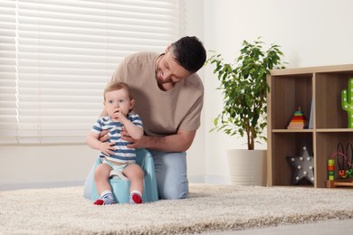 Photo of Father training his child to sit on baby potty indoors. Space for text