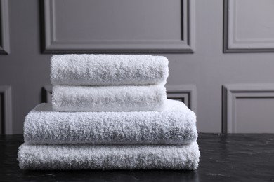 Stacked terry towels on black textured table indoors, space for text