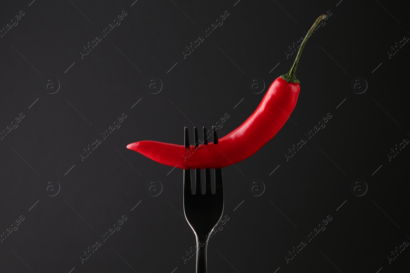 Photo of Fork with chili pepper on black background