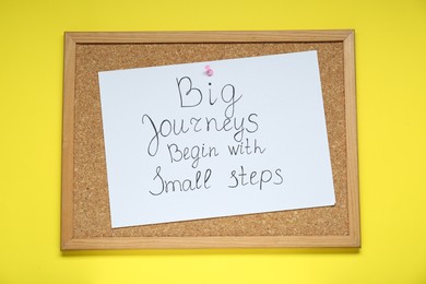 Corkboard with pinned message Big Journeys Begin With Small Steps on yellow background, top view. Motivational quote