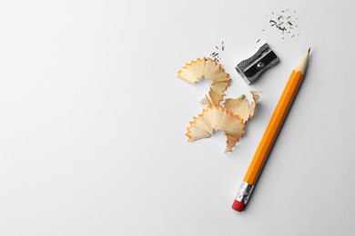 Photo of Graphite pencil, shavings and sharpener on white background, flat lay. Space for text