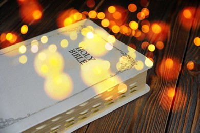 Image of Holy Bible on wooden table, bokeh effect