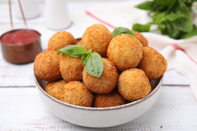 Photo of Bowl of delicious fried tofu balls with basil on white wooden table