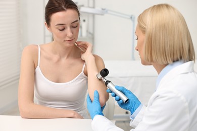 Photo of Dermatologist with dermatoscope examining patient in clinic