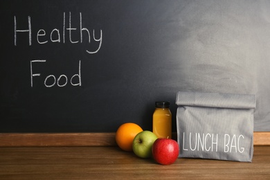 Photo of Lunch for schoolchild on table near blackboard with chalk written Healthy Food
