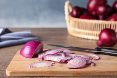 Wooden board with cut fresh red onion on table