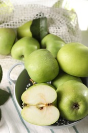 Photo of Fresh green apples with water drops on white striped tablecloth, closeup