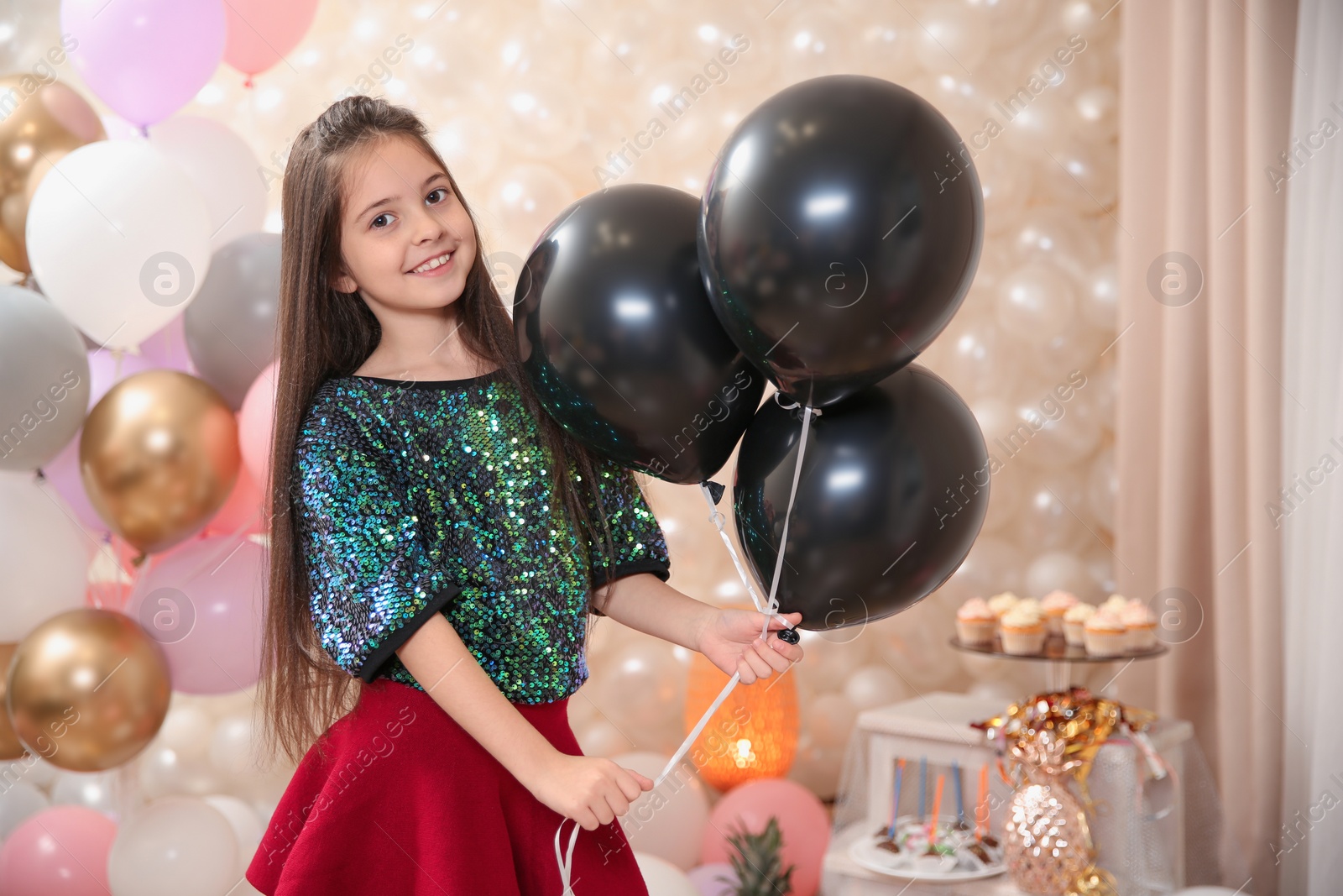 Photo of Happy little girl with balloons in beautifully decorated room at home. Birthday celebration