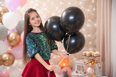 Photo of Happy little girl with balloons in beautifully decorated room at home. Birthday celebration